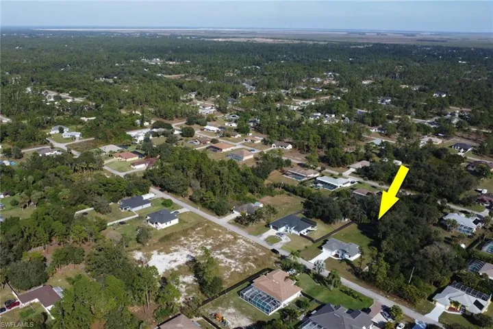 Aerial view of property and surrounding area featuring nearby suburban area and a forest