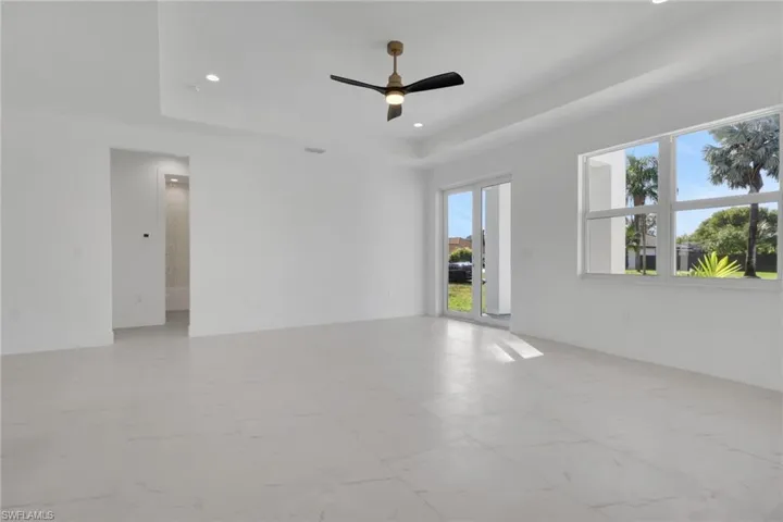 Entry way and dining area featuring light marble finish floors, a ceiling fan, recessed lighting, and a raised ceiling