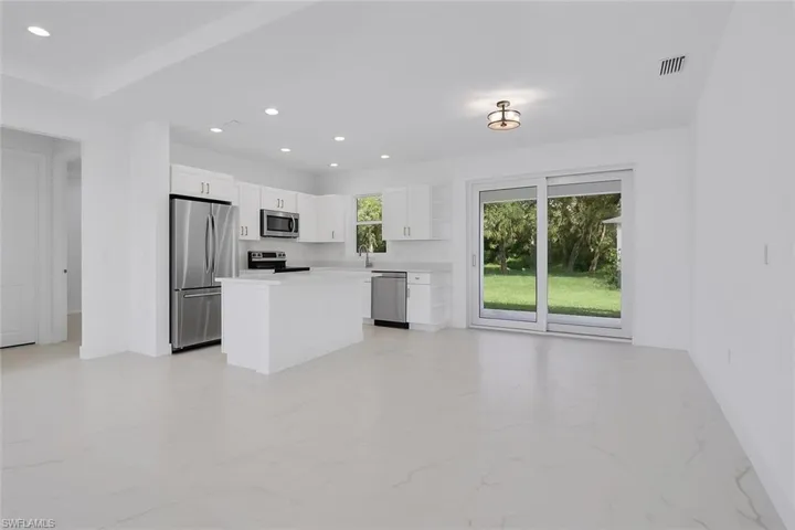 Kitchen with a kitchen island, stainless steel appliances, white cabinetry, light countertops, and recessed lighting