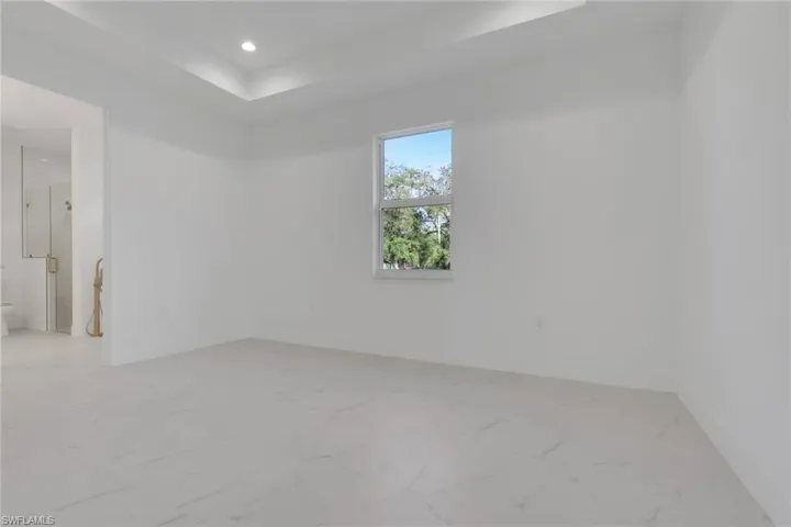 Primary bedroom with light marble finish flooring and recessed lighting