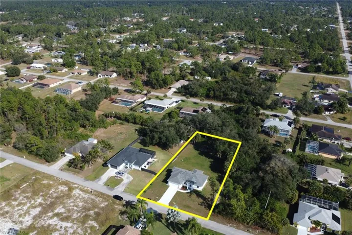 Aerial view of residential area featuring property boundaries highlighted and a forest