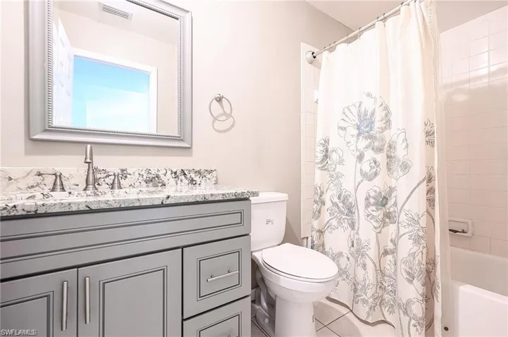 Bathroom with vanity, shower / bath combo with shower curtain, and tile patterned floors