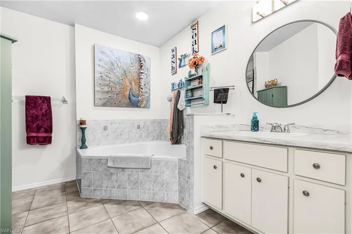 Full bathroom with vanity, a garden tub, and light tile patterned floors
