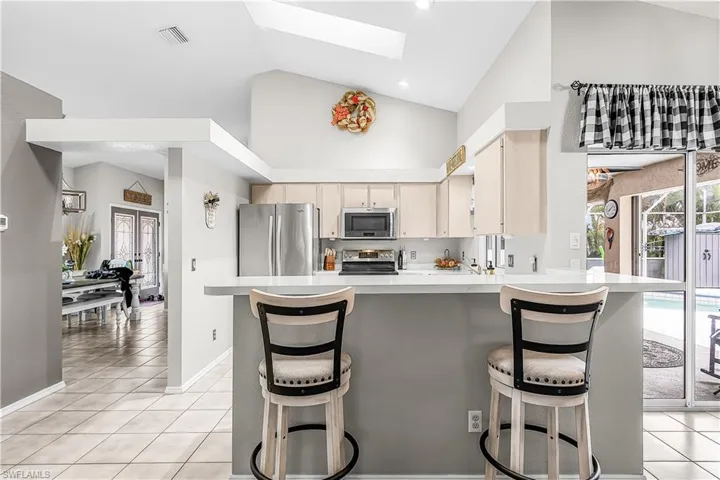 Kitchen featuring a breakfast bar area, light countertops, stainless steel appliances, a skylight, and a peninsula