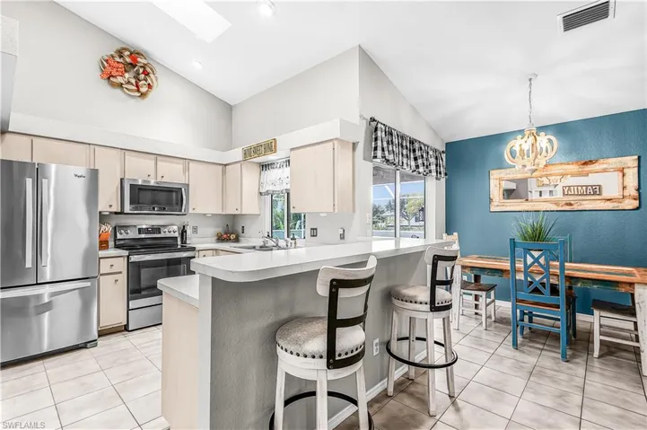 Kitchen with stainless steel appliances, lofted ceiling, a skylight, light countertops, and a kitchen bar