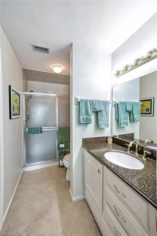 Bathroom with tile patterned floors, vanity, walk in shower, and toilet