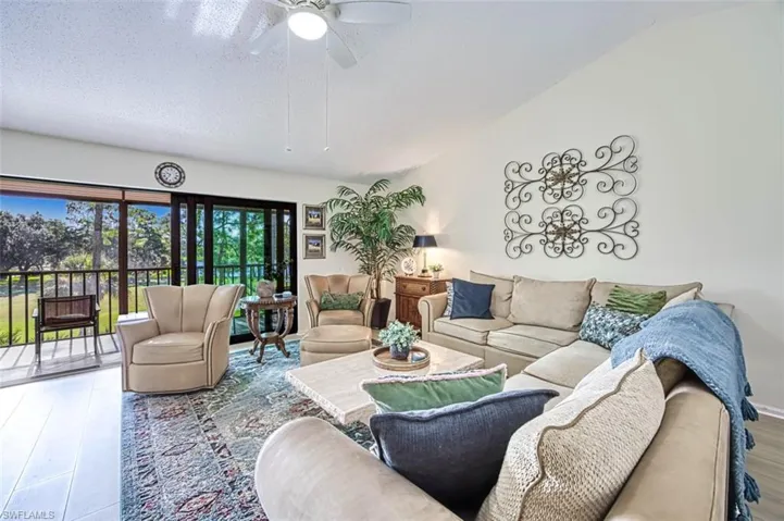 Living room featuring vaulted ceiling, a textured ceiling, ceiling fan, and hardwood / wood-style floors