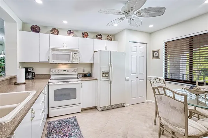 Kitchen with white cabinetry, ceiling fan, white appliances, sink, and light tile patterned floors