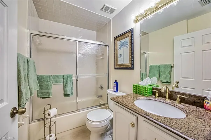 Full bathroom featuring vanity, shower / bath combination with glass door, and toilet