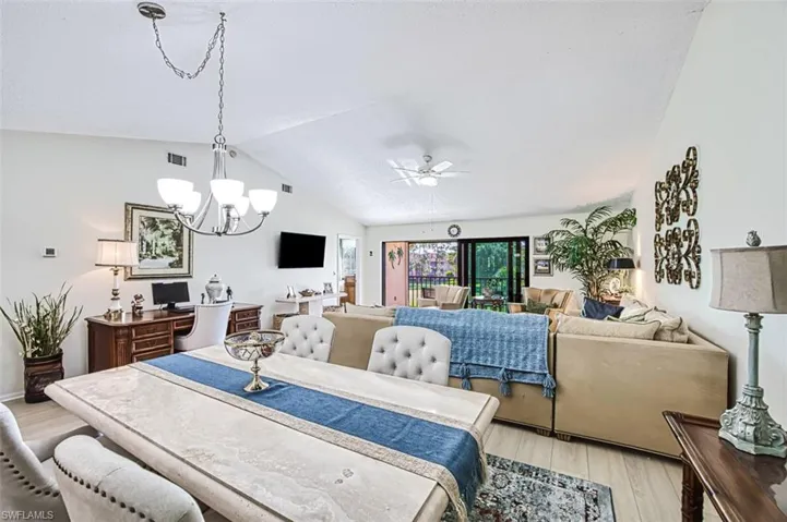 Dining room featuring light hardwood / wood-style floors, lofted ceiling, and ceiling fan with notable chandelier