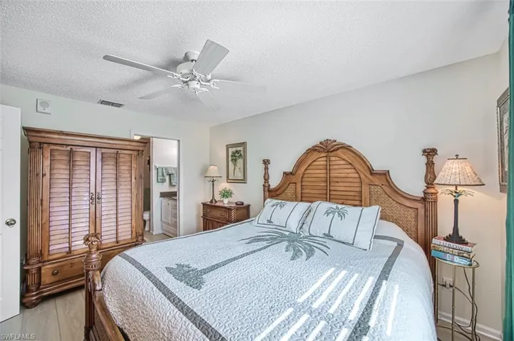 Bedroom featuring ensuite bathroom, a textured ceiling, ceiling fan, and hardwood / wood-style floors