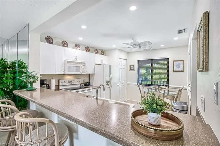 Kitchen featuring ceiling fan, white cabinets, white appliances, sink, and kitchen peninsula