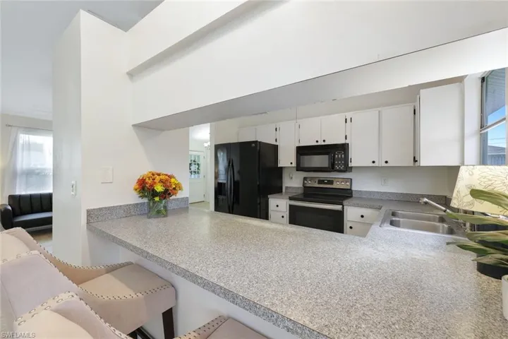 Kitchen features black appliances and white cabinetry, and presents an opportunity to personalize your space.