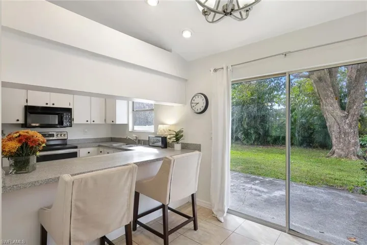 Kitchen features a kitchen breakfast bar, white cabinets, a wealth of natural light, and electric stove