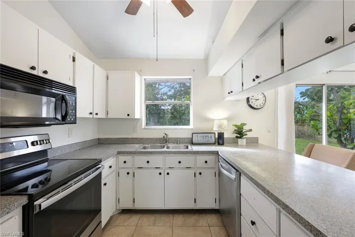 Kitchen features black appliances and white cabinetry, and presents an opportunity to personalize your space.