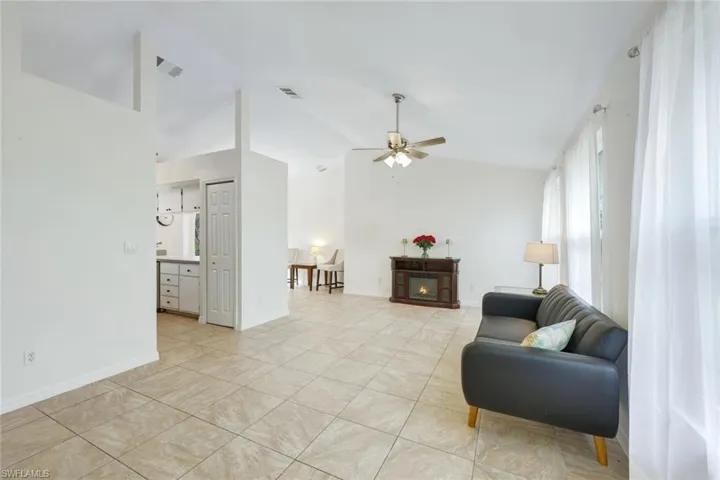 Living room with vaulted ceiling, and large square-format tile throughout.
