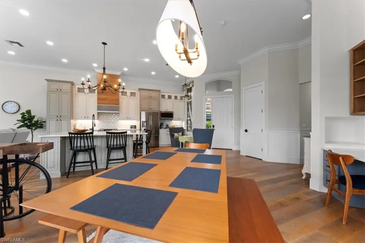 Dining area featuring a chandelier, wood finished floors, crown molding, recessed lighting, and a wainscoted wall