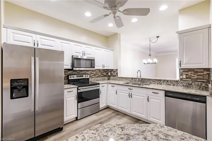 Kitchen featuring stainless steel appliances, white cabinetry, sink, and ornamental molding