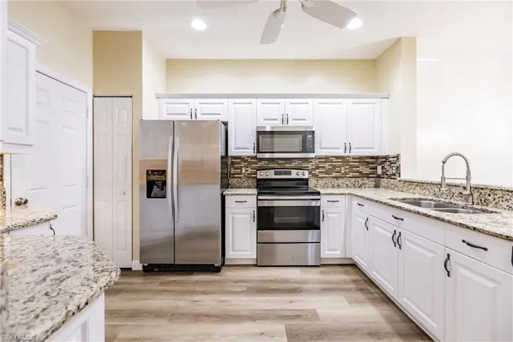 Kitchen with light hardwood / wood-style floors, white cabinetry, sink, and appliances with stainless steel finishes