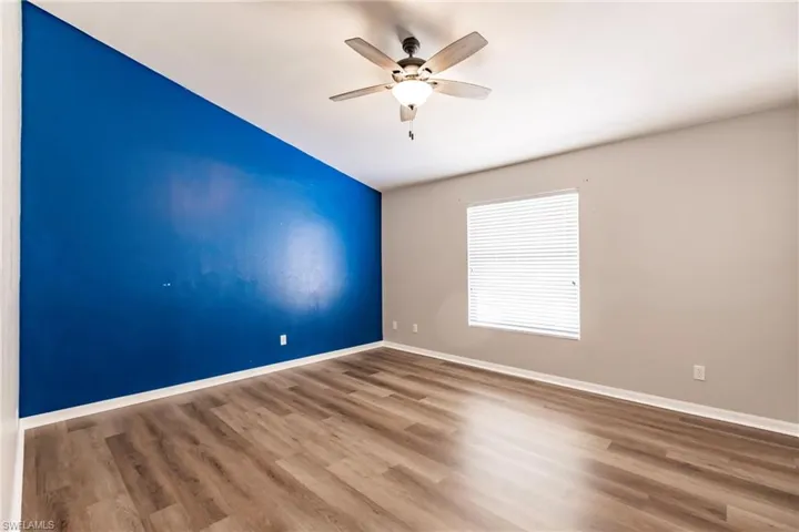 Empty room with wood-type flooring, vaulted ceiling, and ceiling fan
