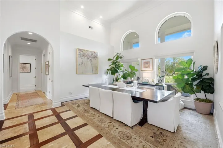 Soaring ceilings with arched windows, recessed lighting, and a patterned tile and wood-finish flooring