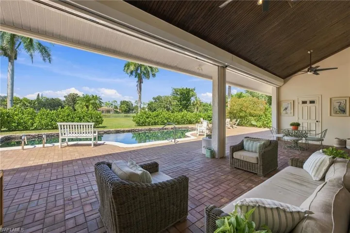 Expansive brick paver patio featuring a swimming pool, outdoor shower, with a surrounding large lawn looking at lake view.