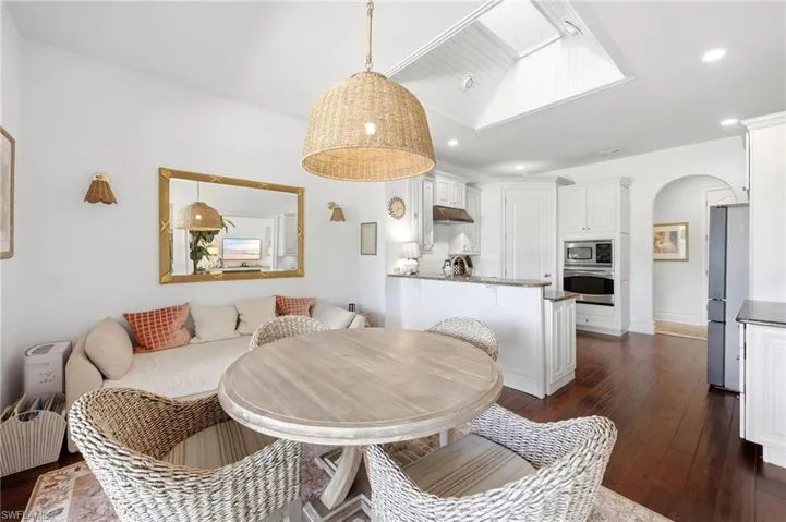 Recessed lighting, wood-finish flooring, white cabinetry, kitchen island with countertop, and skylight
