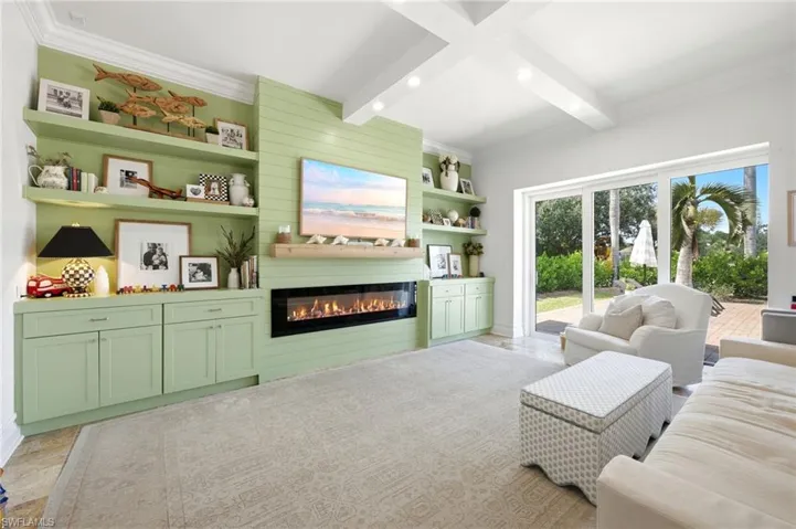 Built-in cabinetry and shelving surround a linear fireplace, tile flooring, sliding glass doors out to patio and pool area