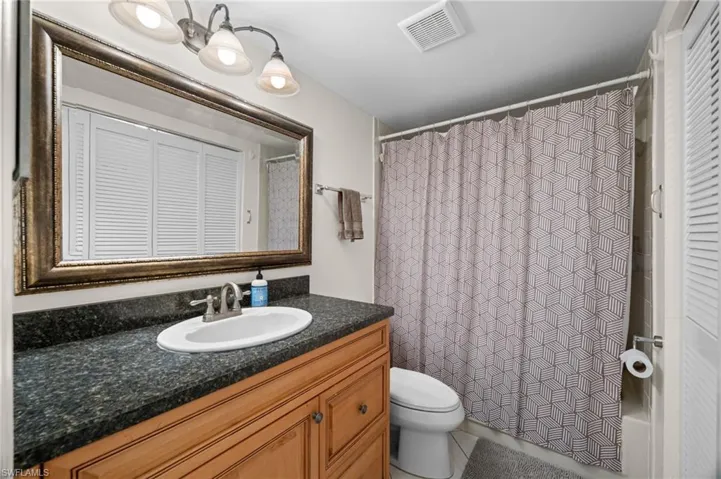 Full bathroom featuring a closet, vanity, a shower with curtain, and tile patterned floors
