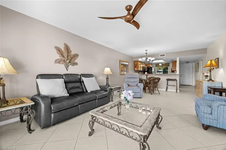 Living area with light tile patterned floors, a chandelier, and ceiling fan