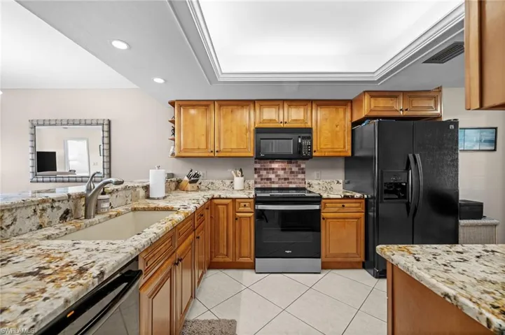 Kitchen with light stone countertops, brown cabinets, and recessed lighting
