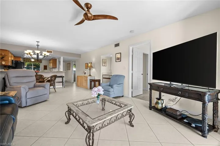 Living room featuring ceiling fan, a chandelier, and light tile patterned floors