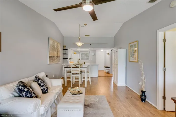 Spacious living area featuring vaulted ceilings, wood-finish flooring, and a ceiling fan with integrated lighting