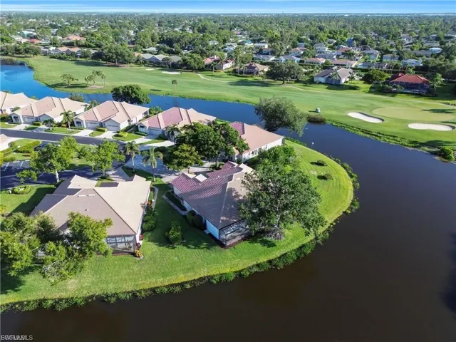 Aerial perspective of suburban area featuring a local golf course and a nearby body of water