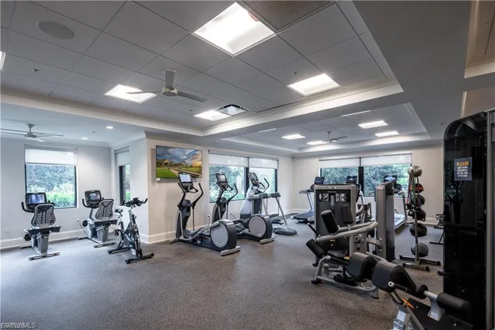 Workout area featuring ceiling fan, ornamental molding, a raised ceiling, and a drop ceiling