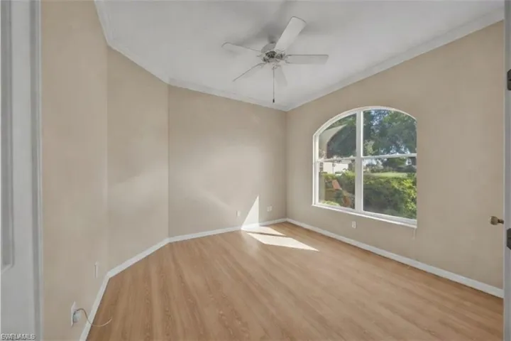 virtually staged den Unfurnished office room with light wood finished floors, ceiling fan, and crown molding