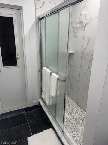 Bathroom with a shower with shower door and tile patterned flooring