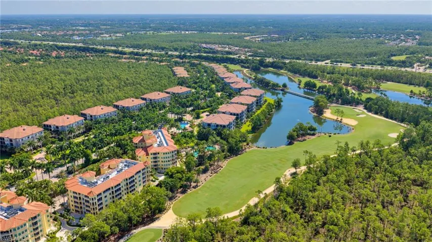 Expansive golf course property featuring multiple residential buildings with terracotta tile roofs, surrounded by dense green landscaping and a winding water feature