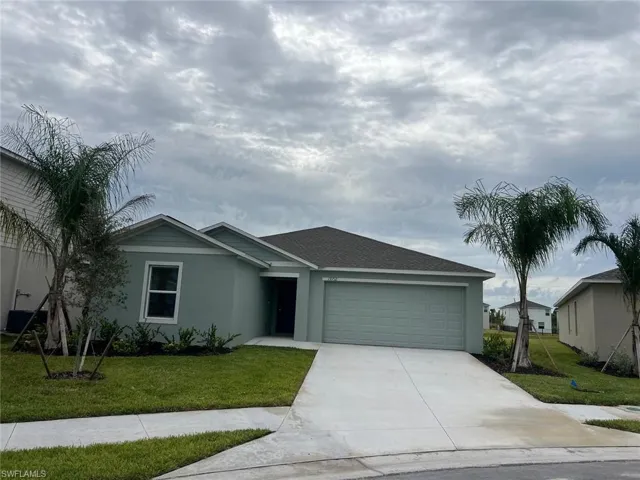 Ranch-style house featuring a front lawn, driveway, a garage, and stucco siding