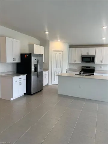 Kitchen with white cabinetry, light countertops, appliances with stainless steel finishes, and light tile patterned flooring