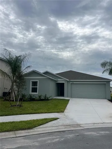 Ranch-style house featuring a garage, concrete driveway, stucco siding, a front lawn, and roof with shingles