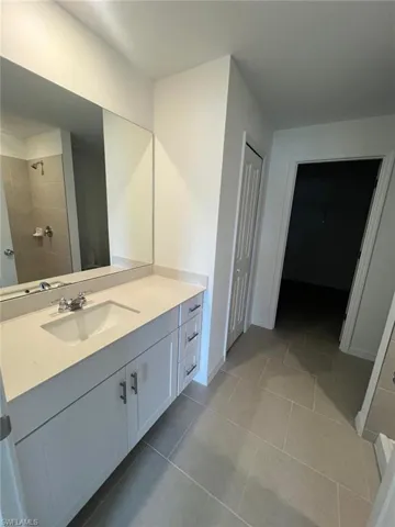 Bathroom with vanity, a closet, light tile patterned flooring, and tiled shower