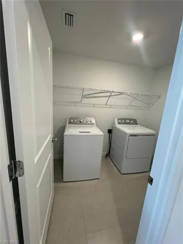 Laundry area featuring light tile patterned floors and washer and dryer
