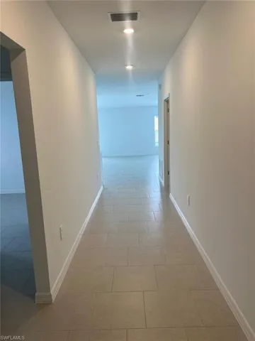 Corridor with light tile patterned floors and recessed lighting