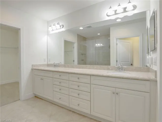 Primary Bathroom With Long Vanity, Quartz Counters, Drawer Bank,  & Door To Walk In Closet