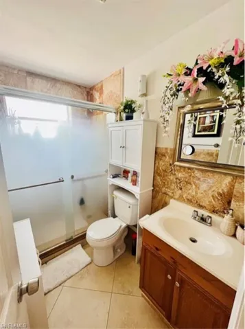 Full bath with vanity, a stall shower, light tile patterned flooring, and tile walls
