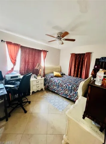 Bedroom featuring light tile patterned flooring, ceiling fan, and a desk