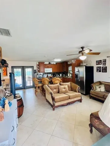 Living room featuring ceiling fan, french doors, and light tile patterned floors