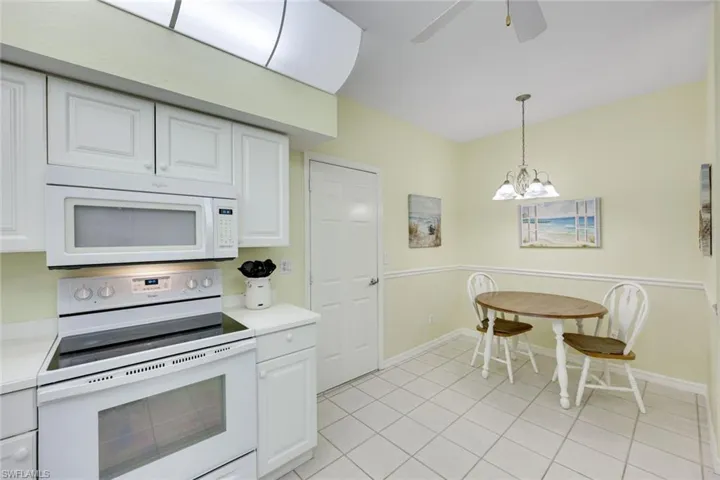 Kitchen with white appliances, white cabinets, decorative light fixtures, light countertops, and light tile patterned flooring
