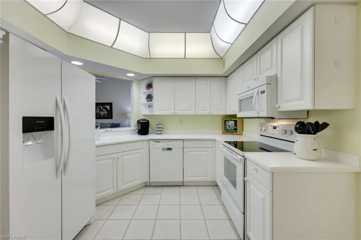 Kitchen with white appliances, light countertops, white cabinetry, a sink, and light tile patterned flooring